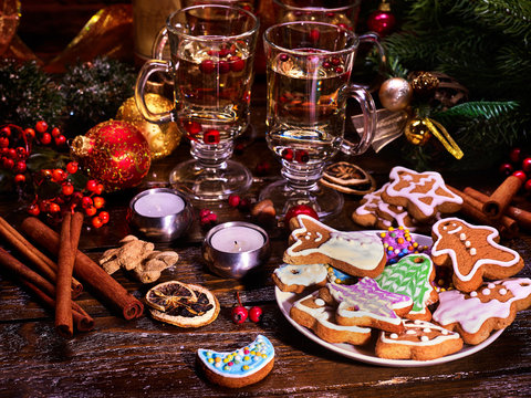 Christmas still life with Christmas cookies, close-up. Two glasses of hot punch standing on wooden table. Canella, candles and Christmas tree.