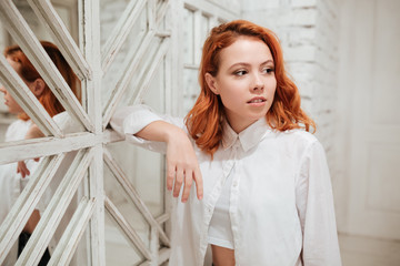 Beautiful redhead young woman standing near mirror in cafe