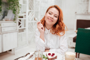 Young redhead pretty woman eating cake in cafe
