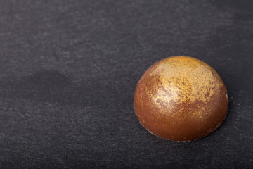 One chocolate candy on a slate background