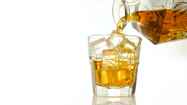 Whiskey on the rocks poured from a rystal decanter on white backround with copy space
