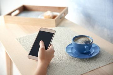 Woman with modern cellphone at table