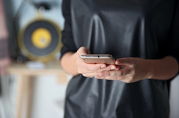 Woman holding modern cellphone at home