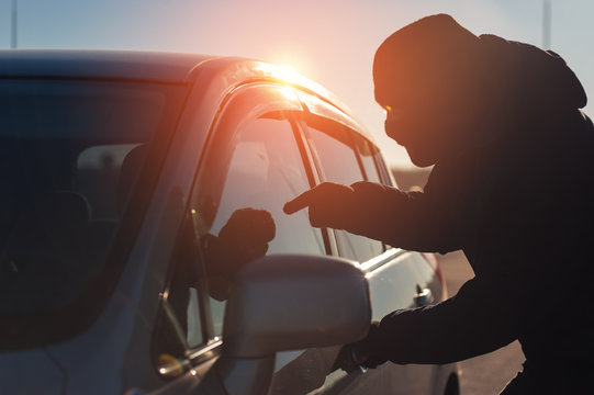 Male thief in black balaclava pointing to driver