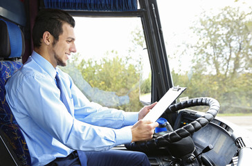Handsome driver with clipboard sitting in bus