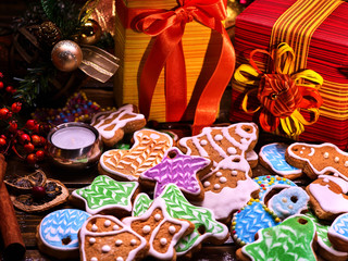 Christmas celebration for family. Christmas gift box under and lots of colored gingerbread Christmas cookies in foreground.