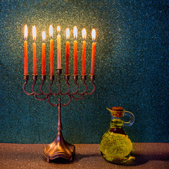 Major traditional Jewish symbols for Hanukkah holiday: menorah and jar of olive oil. Low key image slightly toned for inspiration of retro style and feast ceremony