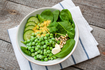 Ingredients for Green peas spinach basil pesto in a white bowl on a wooden background. Love for a healthy raw food concept.
