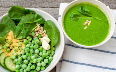 Green peas spinach basil pesto and Ingredients in a white bowl on a wooden background. Love for a healthy raw food concept.