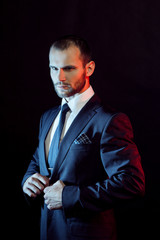 serious man in a business suit, dark background, backlight blue and red tones