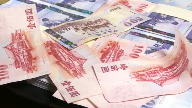 Hundred dollar bills falling on thousand New Taiwan Dollar stacks
