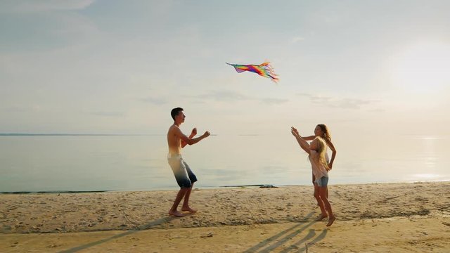 Two sisters run for the older brother, who is launching a kite. Happy family and carefree childhood