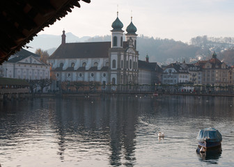 Svizzera, 08/12/2016: un cigno e lo skyline di Lucerna con la Chiesa dei Gesuiti vista dal Ponte della Cappella 