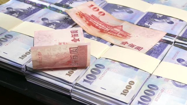 Hundred dollar bills falling on thousand New Taiwan Dollar stacks