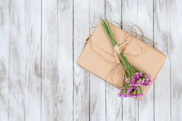 Eco style gift box with dried flowers over wooden background. Top view.