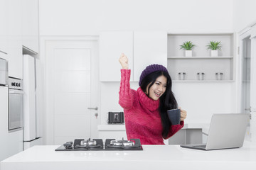 Cheerful woman with laptop in kitchen