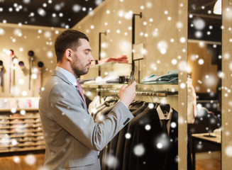 man in suit with smartphone at clothing store