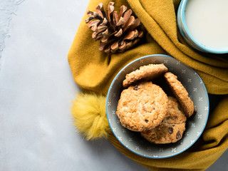 Mug of tea with milk and cookies in a soft winter scarf