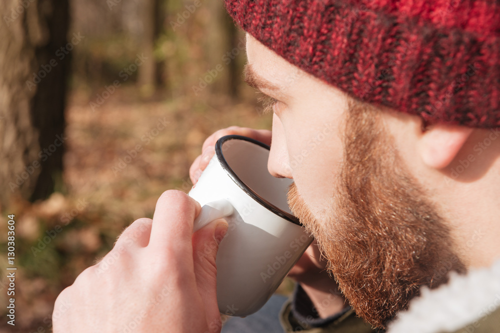 Wall mural handsome bearded man standing in the forest and drinking tea.