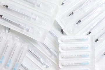 New syringes and needles lie on the surface, packed in bags.
