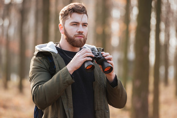 Concentrated serious bearded man holding field-glass