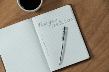 New year resolutions written on diary with coffee mug