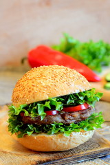 Sandwich with a fried bean burger, lettuce, red bell pepper and cucumber. Wholesome sandwich on a wooden board, fresh vegetables. Simple vegan sandwich idea. Vintage style. Closeup 