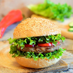 Sandwich with a bean burger, fresh lettuce, red bell pepper and cucumber. Healthy sandwich on a wooden board, fresh vegetables. Simple vegetarian sandwich idea. Vintage style. Closeup