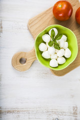 Mozzarella in a green plate on a wooden table. Mozzarella balls