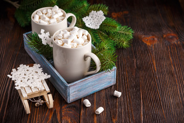 Two cups with small marshmallows on a dark wooden background