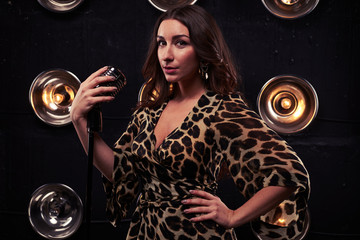 Half-turned model in a chiffon leopard dress holding a silver st