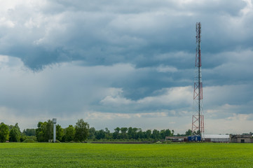 tower of mobile communication and telecommunication in rural areas against the background of the cloudy sky