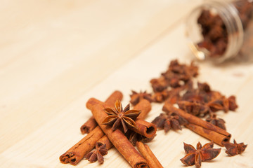 seasoning cinnamon (Cinnamomum), anise (Anisium vulgare Gaerto) and lemon lies on a light wood surface, spilled from a jar,  close-up, background, healthy lifestyle