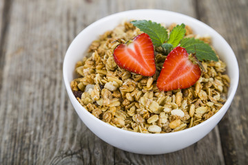 Granola with strawberry on a wooden table. Healthy eating for br
