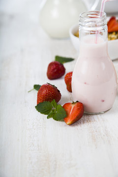 Smoothies and ripe strawberry on a wooden table. Milk drink with