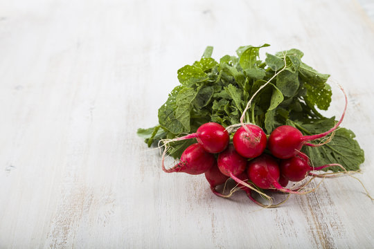 Ripe red radish with leaves on a wooden table close-up. Fresh ve