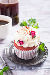 Dessert for Valentines Day, beautiful red velvet cupcake decorated with pink rose on old white wooden background with copy space.