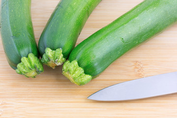 Italian squash plus knife on a wood cutting board.