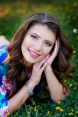 beautiful happy woman lying on the grass with yellow flowers