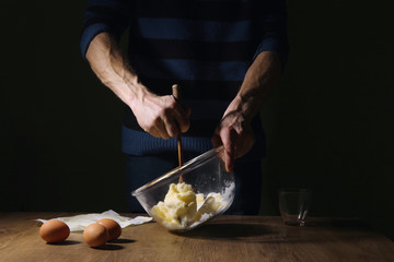 Man hands breaking an egg. Step of making cooking cake, preparing dough. Ingredients: butter, sugar, eggs.
