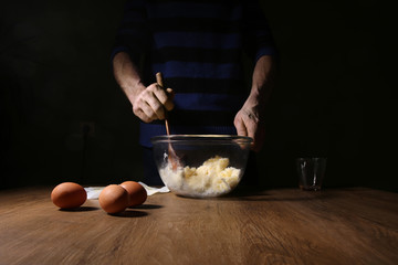 Man hands breaking an egg. Step of making cooking cake, preparing dough. Ingredients: butter, sugar, eggs.
