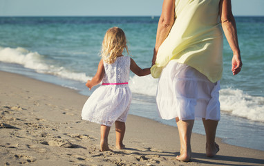 Happy grandmother with little girl walk at beach