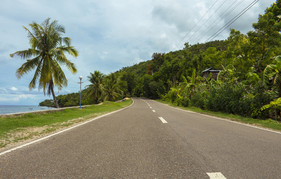 Highway on tropical island. Coastal road in the afternoon. Empty road by the seaside.