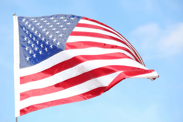 Fototapeta premium Ruffled American flag on blue sky background