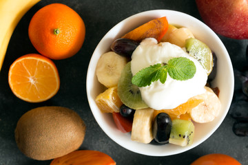 Bowl of healthy fresh fruit salad on black chalkboard