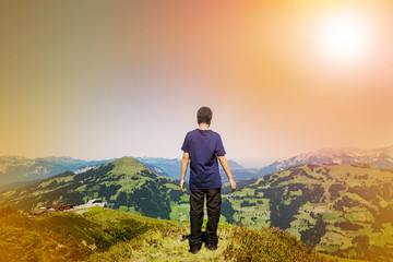 Fototapeta premium Young boy admiring the nature from the peak of the mountain