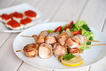 Roasted salmon meat pieces wrapped in bacon slices