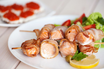 Roasted salmon meat pieces wrapped in bacon slices
