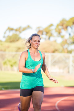 Fit female athlete running a sprint race on a tartan athletics track
