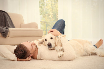 Handsome man with dog  lying on carpet at modern room interior